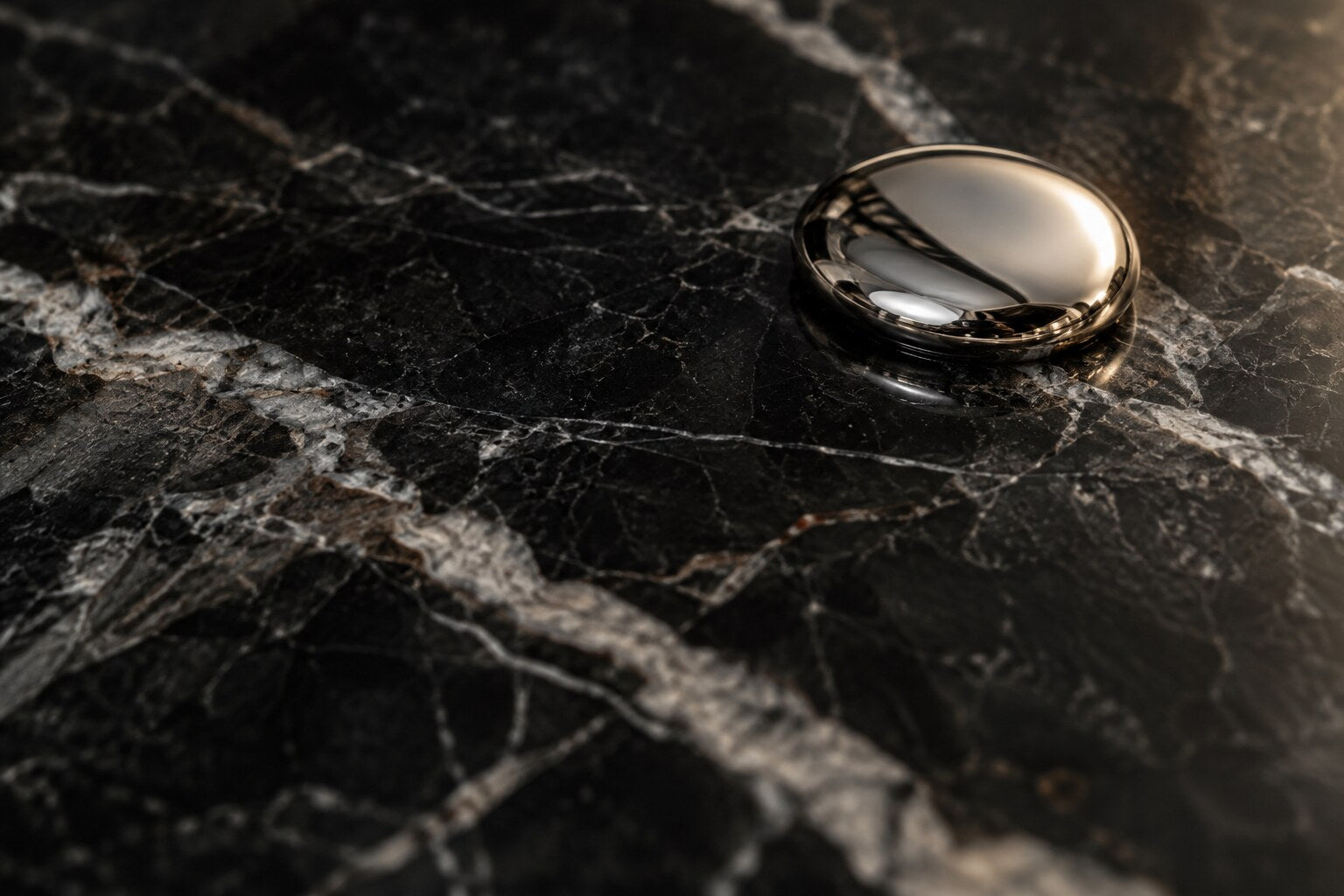 Polished metal droplet on black marble